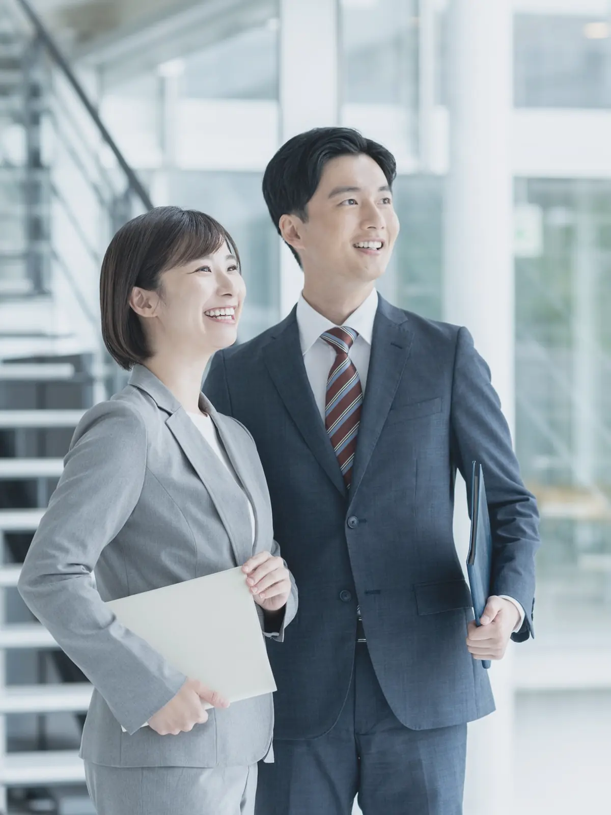 オフィスの階段前で並んで歩く男女(引き)