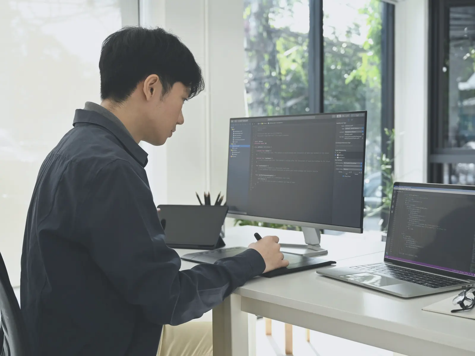 窓際の席でコードを書く開発者